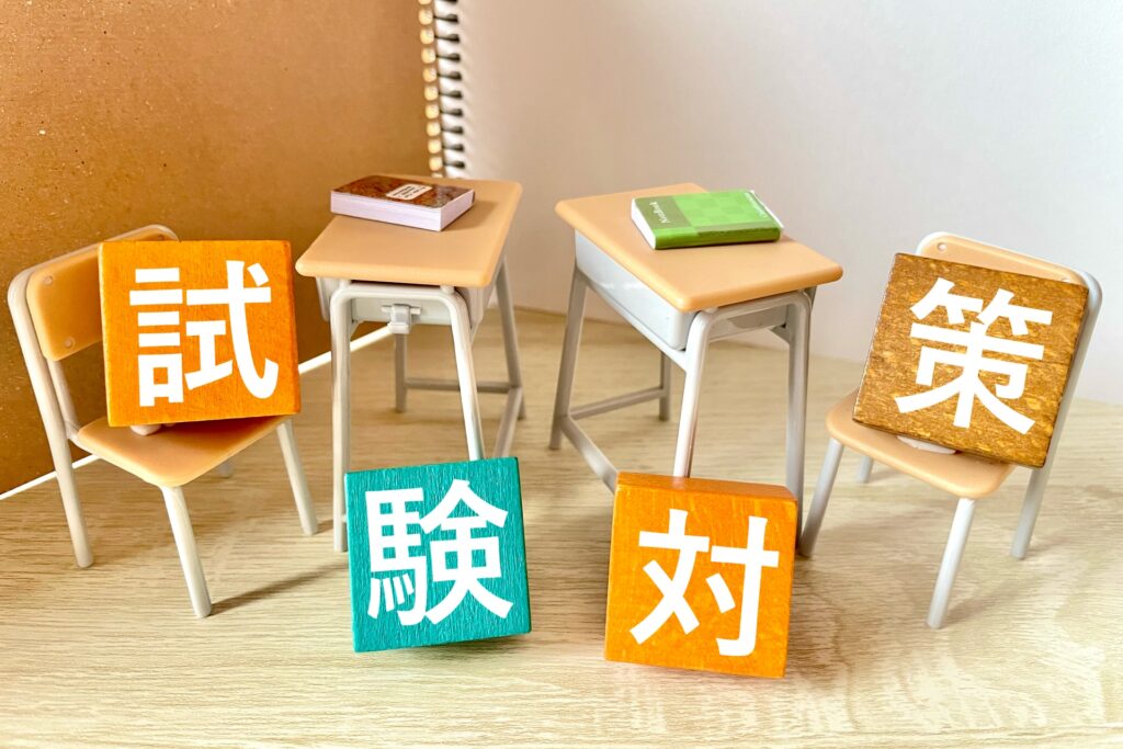 産業ケアマネ資格を取得するための試験対策。ミニチュアの学習机と椅子に置かれた試験対策の文字ブロック