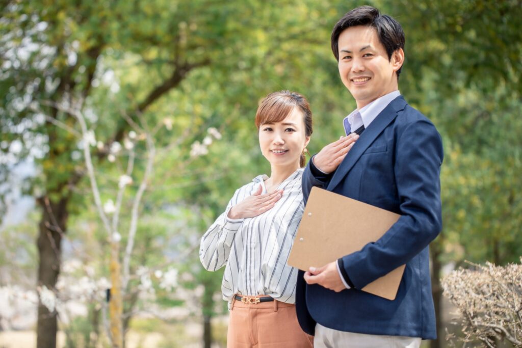 産業ケアマネとして働く男女が屋外で胸に手を当てて微笑む様子。将来性ややりがいのある資格